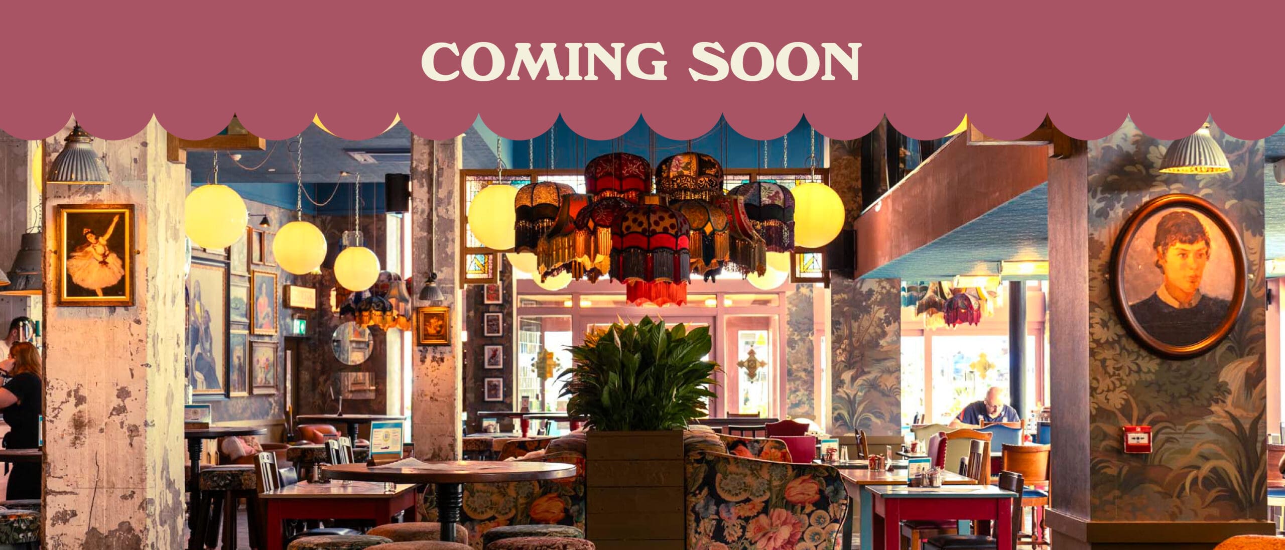 A colorful, vintage-style restaurant interior with eclectic decor, cozy seating, and hanging lamps evokes a charming marinero vibe. Framed art adorns the walls, while a pink banner at the top reads “COMING SOON.”.