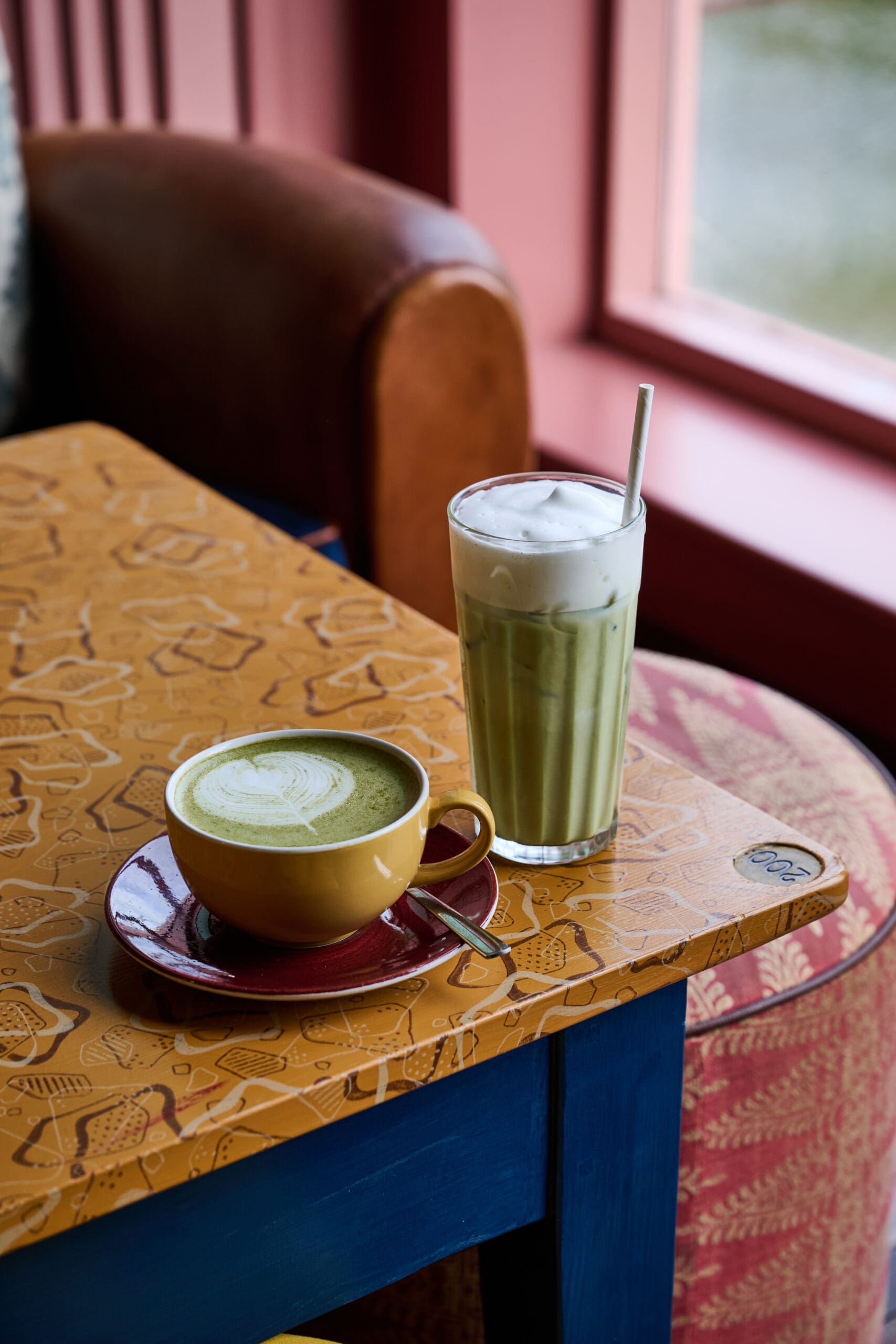 A cup of green tea and a glass of green tea on a table.